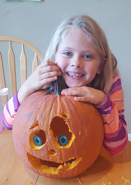 Smiling 2nd grader with carved pumpkin